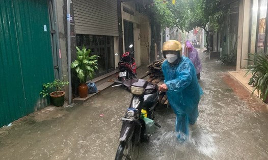 Tại phố Bùi Xuân Trạch, mưa lớn khiến nước ngập cao đến đầu gối, xe máy đi qua tuyến đường bị chết máy. Ảnh Phạm Đông