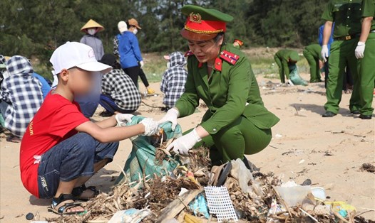 Cháu bé theo mẹ tham gia gom rác bãi biển - Đây cũng là dịp để các nữ đoàn viên Công đoàn giáo dục cho con trẻ về ý thức bảo vệ môi trường. Ảnh: CĐ Công an tỉnh Nghệ An.