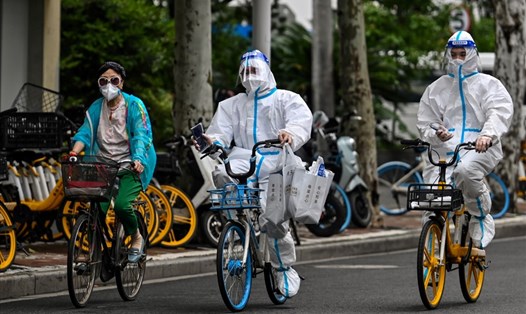 Công nhân mặc thiết bị bảo hộ đạp xe trên đường phố quận Tĩnh An, Thượng Hải ngày 29.5.2022. Ảnh: AFP