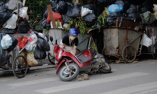 Người dân đi xe máy bị té ngã do bị vướng tầm nhìn của xe rác. Ảnh: Thu Hiền