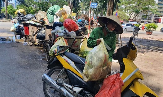 Công nhân dùng cả xe máy để vận chuyển do lượng rác thải chất đống, bốc mùi hôi thối trên nhiều tuyến phố Hà Nội. Ảnh: Phạm Đông