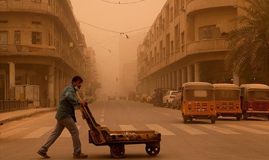 Một người đàn ông đẩy xe hàng trong cơn bão cát ở Baghdad, Iraq, ngày 23.5. Ảnh: AP.
