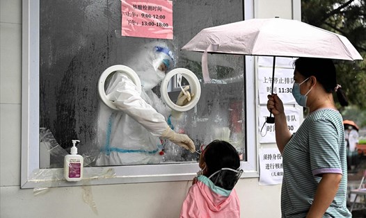 Nhân viên y tế lấy mẫu xét nghiệm COVID-19 cho một em nhỏ ở Bắc Kinh, Trung Quốc, ngày 22.6. Ảnh: AFP