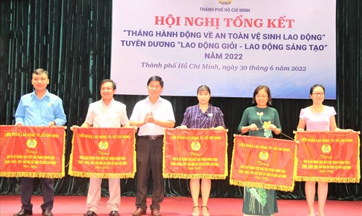 Phó Chủ tịch LĐLĐ TPHCM Phạm Chí Tâm (thứ ba từ trái qua) trao cờ của LĐLĐ TPHCM cho các tập thể có thành tích xuất sắc trong phong trào "Xanh - Sạch - Đẹp, Bảo đảm an toàn vệ sinh lao động". Ảnh: Nam Dương