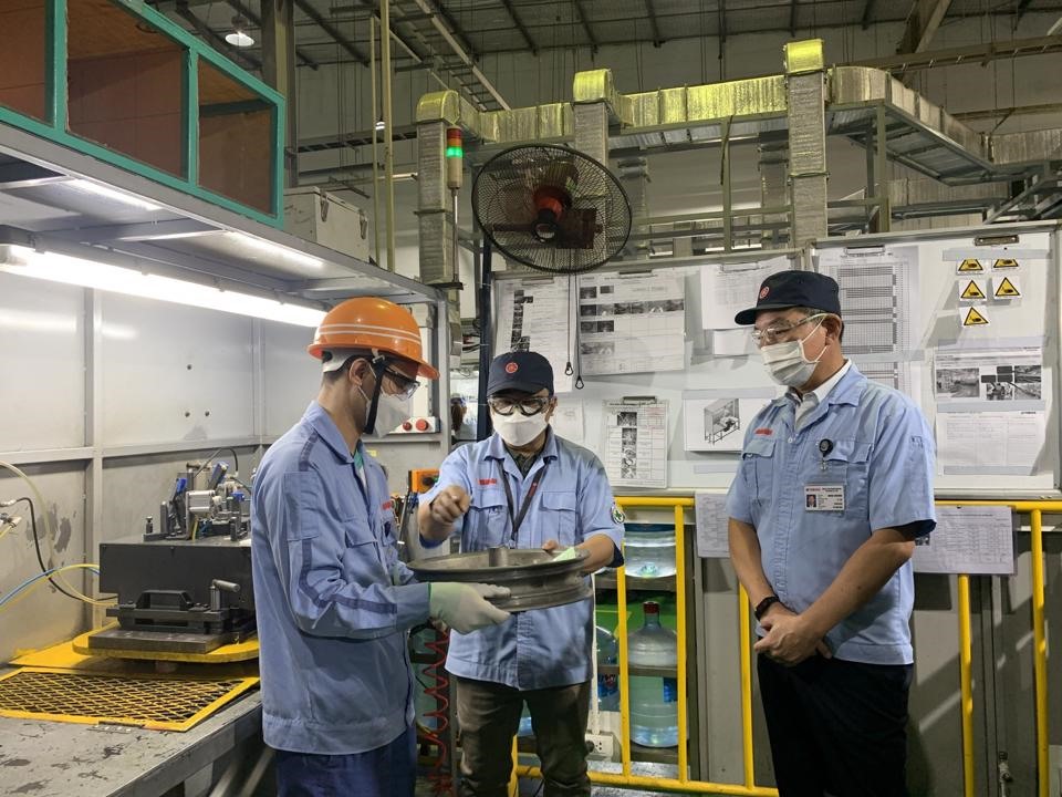 Anh Phạm Văn Tư (bên trái) chia sẻ về sáng kiến cải tiến của mình với lãnh đạo công ty. Ảnh: Phạm Đông
