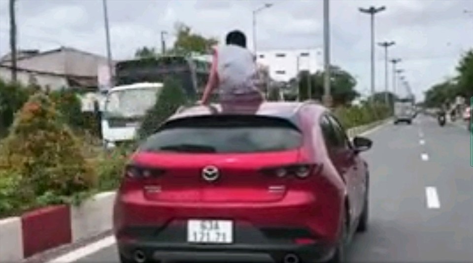 Cảnh trẻ em ngồi trên nóc ô tô đang di chuyển trên Quốc lộ gây bất an cho người đi đường. Ảnh cắt từ clip người dân ghi lại