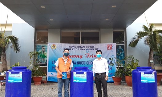Anh Nguyễn Văn Việt trao bồn chứa nước cho công nhân giúp giảm bớt khó khăn do hạn mặn. Ảnh: G.C