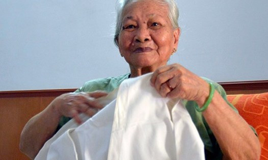 Bà Lê Thị Muộn cùng kỷ vật là chiếc áo của liệt sĩ Phan Văn Sự. Ảnh: Tư liệu