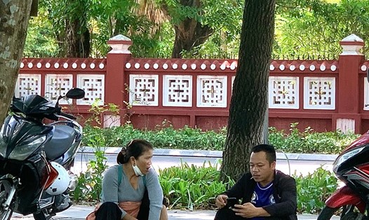 Hai vợ chồng trẻ ngồi chờ con thi tốt nghiệp THPT năm 2022 ở góc công viên Lê Lợi (TP. Huế).