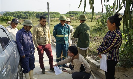 Phóng viên Quang Đại (người ngồi) trao đổi với người dân trong một lần tác nghiệp tại thị xã Hoàng Mai - Nghệ An. Ảnh: HT