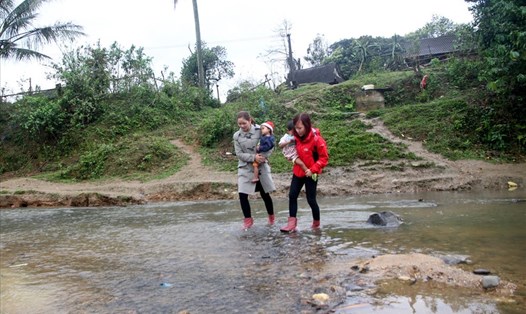 Giáo viên ở huyện miền núi Hướng Hóa (tỉnh Quảng Trị) lội suối đi đón học sinh trở lại trường sau kỳ nghỉ. Ảnh: Hưng Thơ.
