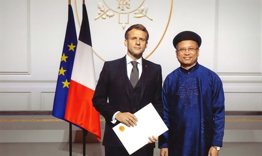 Đại sứ Đinh Toàn Thắng trong trang phục áo dài trình quốc thư và chụp ảnh chung với Tổng thống Pháp năm 2021. Ảnh: Đại sứ quán Việt Nam tại Pháp