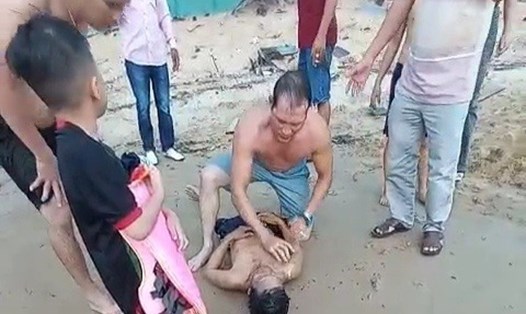 Ông Thái đã bị đuối nước sau khi bơi ra cứu 2 cháu bé và được người dân sơ cứu. Ảnh cắt từ clip.
