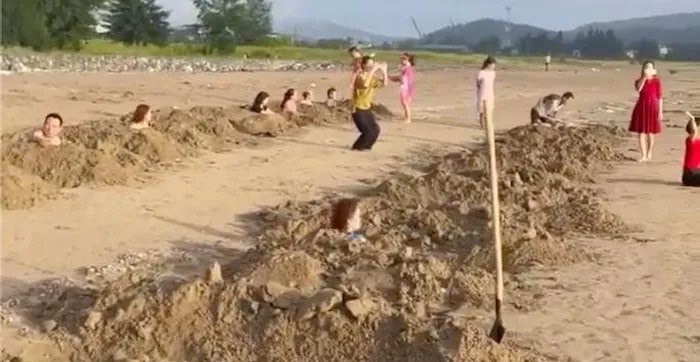 Nhóm du khách đào nhiều hố cát trên bãi biển rồi nằm vào, gây ra nhiều ý kiến trái chiều. Ảnh: CMH