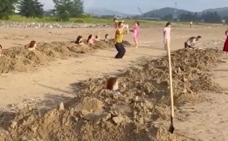 Nhóm du khách đào nhiều hố cát trên bãi biển rồi nằm vào, gây ra nhiều ý kiến trái chiều. Ảnh: CMH