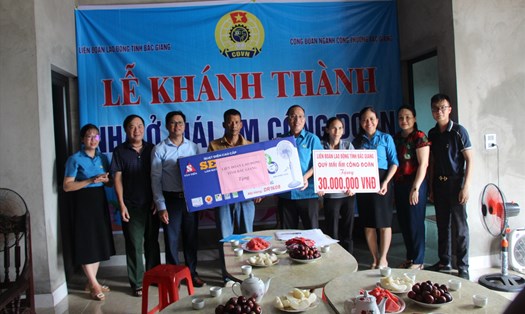 Ông Lê Đức Thọ, Phó Chủ tịch Liên đoàn Lao động tỉnh (thứ 5 từ phải qua) trao hỗ trợ kinh phí và phần quà cho gia đình chị Nghĩa.