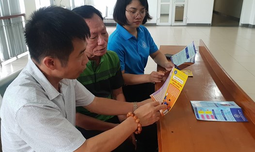 Đại diện các cơ quan chức năng quận Long Biên chia sẻ về tính ưu việt của chính sách BHXH tự nguyện cho một thành viên thuộc hộ cận nghèo (người ở giữa) trên địa bàn. Ảnh: Hà Hiền