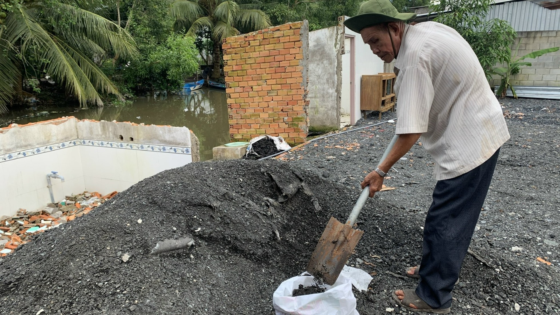 Ông Chín Song đang hót vội đá để đi vá đường. Ảnh: Hồ Thảo