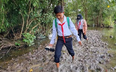 Em Triệu Minh Thạch cùng bạn lội sình đi học mỗi ngày. Ảnh: Văn Sỹ