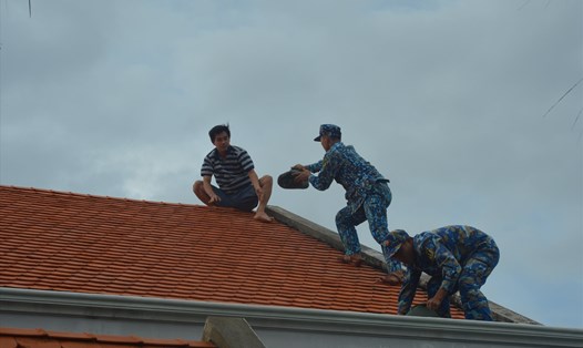Cán bộ, chiến sĩ đảo Sinh Tồn giúp nhân dân chằng buộc mái nhà phòng chống bão Noru. Ảnh: N.Ninh