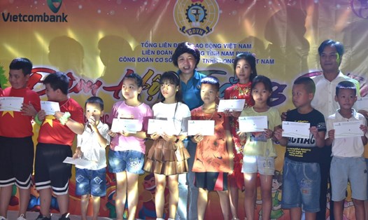 Đại diện Quỹ XHTT Tấm lòng Vàng, nhà tài trợ Vietcombank và lãnh đạo LĐLĐ tỉnh Nam Định trao học bổng cho các cháu học sinh. Ảnh: T.D