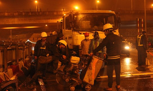 Công nhân xây dựng đội mưa xuyên đêm sửa chữa mặt đường. Ảnh: LĐ
