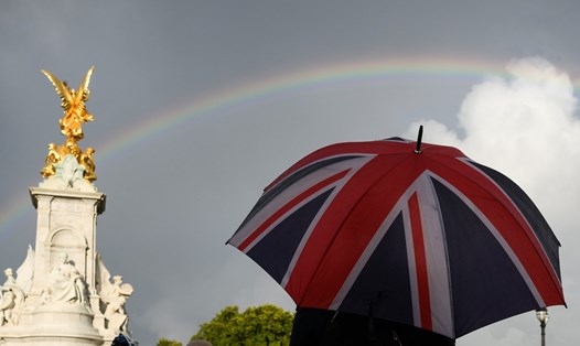 Một người cầm ô in hình quốc kỳ Anh đứng tại Đài tưởng niệm Victoria ngày 8.9. Ảnh: AFP
