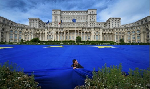 Một người đàn ông trải lá cờ khổng lồ của Liên minh Châu Âu trước tòa nhà quốc hội Romania ở Bucharest. Ảnh: AFP