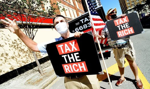Hai người biểu tình của nhóm MoveON kêu gọi tăng thuế với người giàu và các tập đoàn ở Tampa, Florida, tháng 5.2021. Ảnh: AFP
