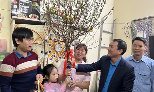 Gia đình chị Lê Thị Hồng nhận cành đào và quà hỗ trợ Tết từ "bác Toản" (thứ hai từ phải sang). Ảnh: Linh Nguyên