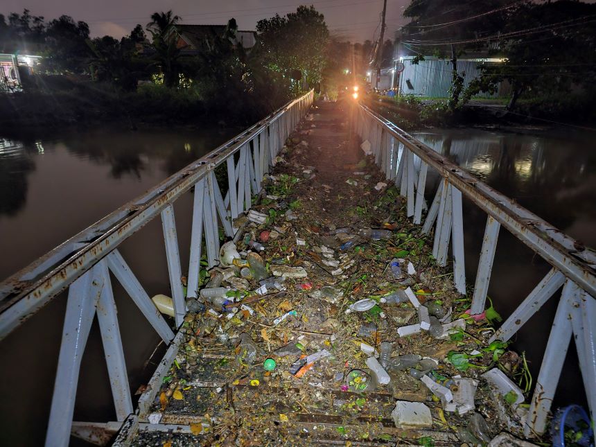 Một cây câu dân sinh còn lại, nước cuốn theo rác thải còn đọn ở trên cầu.