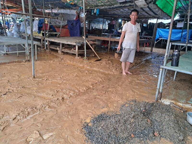 Các tiểu thương tranh thủ dọn bùn non khi trời ngớt mưa. Ảnh: Nguyễn Linh