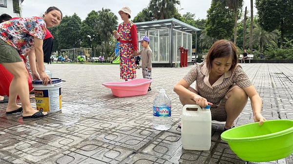 Cư dân ở chung cư trong khu đô thị Thanh Hà phải dùng xô chậu đi lấy nước sạch. Ảnh: Anh Huy.