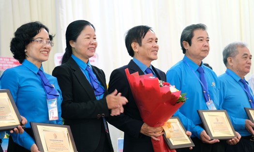 Bà Huỳnh Thị Tuyết Vui (thứ 2 trái sang) tặng hoa và biểu trưng lưu niệm cho ông Trần Hoàng Vũ (thứ 3 trái sang). Ảnh: Tùng Linh