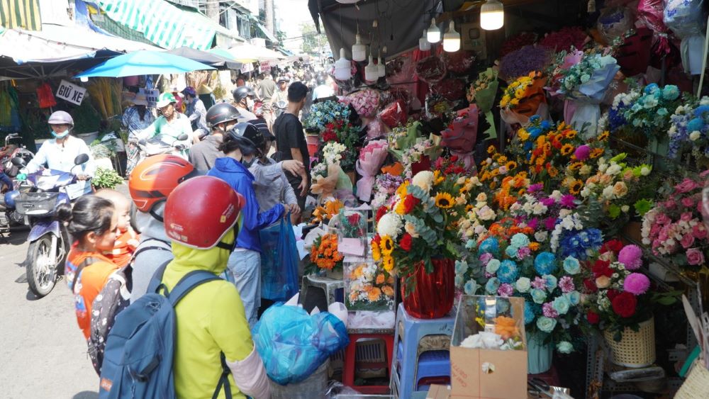 Các tiệm hoa tươi, hoa sáp tấp nập khách đến lựa chọn và hỏi giá. Trong đó, phần lớn là giới trẻ tới chợ đích thân chọn hoa, mong muốn dành món quà bất ngờ đến những người phụ nữ quan trọng.