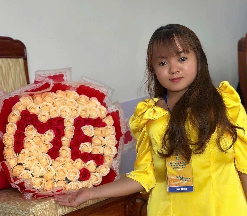 Cô gái xương thủy tinh Bùi Thị Yến Nhi (Ngã Sáu, Châu Thành, Hậu Giang) bên sản phẩm hoa sáp do chính chị thực hiện. Ảnh: NVCC