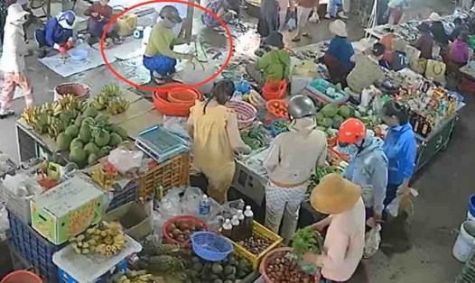 Camera ghi lại cảnh Nguyễn Thị Chi xách thùng nhựa trong chợ.