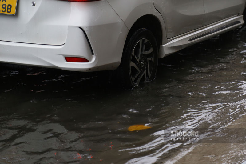 Nước ngập 1/3 bánh xe ôtô đang đậu bên lề đường.