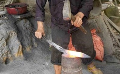 Lò rèn của người Mông không cầu kỳ, chỉ có một ụ đất làm lò, vài cục sắt to làm đe và một cái bễ. Ảnh: Anh Vũ