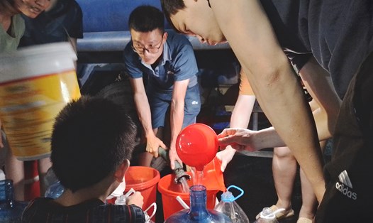 Cư dân khu đô thị Thanh Hà xếp hàng hứng từng giọt nước sạch mang về sử dụng. Ảnh: Khánh Linh