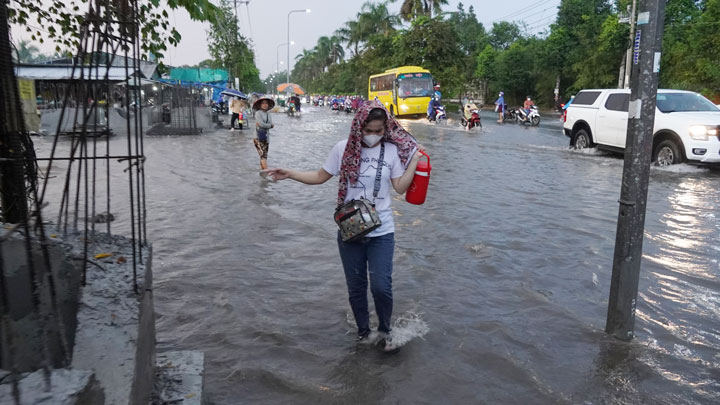 Công nhân dò dẫm men theo vỉa hè để tránh đoạn ngập sâu.