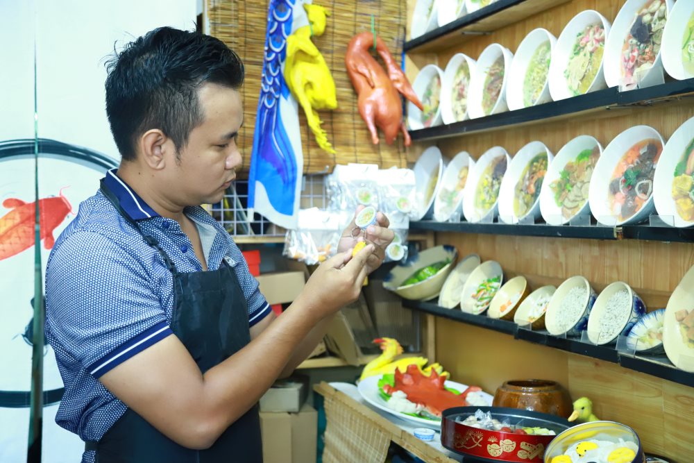 Anh Nguyễn Tấn Đạt là nghệ nhân vẽ tranh cá 3D được 4 năm, với hơn 12.000 tác phẩm. Năm 2019, tận dụng thời gian rảnh nghỉ dịch ở nhà, anh Đạt xem lại các tư liệu ghi nhận về văn hóa ở miền Tây. Từ đó, anh quyết tâm thực hiện các mô hình món ăn của Việt Nam bằng đất sét để quảng bá những giá trị văn hóa của quê hương.
