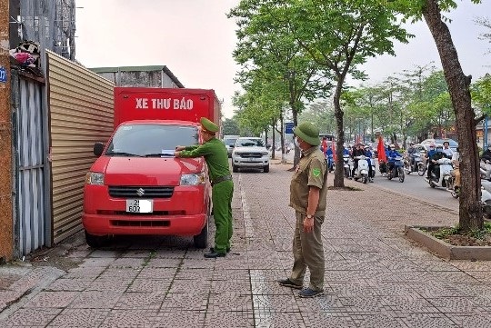 Công an phường Thạch Bàn, quận Long Biên xử lý, nhắc nhở đối với xe ô tô vi phạm đỗ trên vỉa hè. Ảnh: Hanoi.gov.vn  