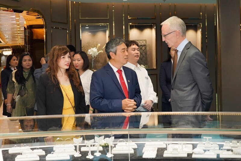 Phó Tổng Giám đốc Dương Anh Tuấn (mặc vest, bên trái) giới thiệu với ông David Tait và đoàn đại biểu những thiết kế trang sức đẳng cấp, hiện đại, dẫn đầu xu hướng của DOJI.