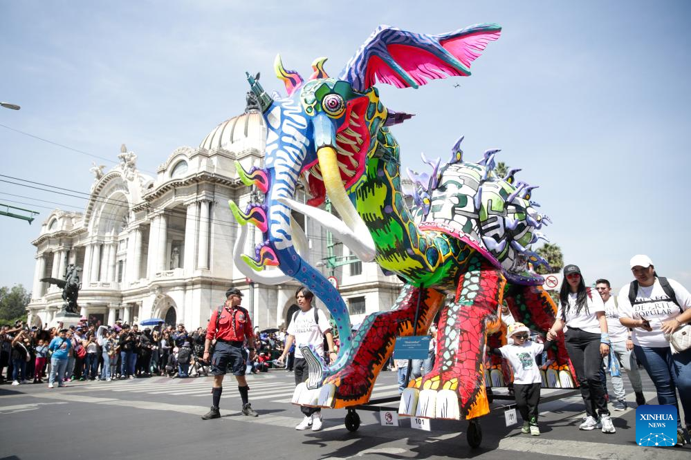 Trong hình là một sinh vật Alebrije, đầu rồng nhưng mang vòi và ngà voi, mình ốc sên đang diễu hành trên phố. Ảnh: Xinhua