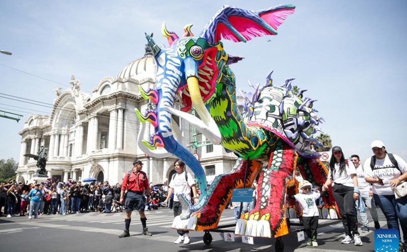 Trong hình là một sinh vật Alebrije, đầu rồng nhưng mang vòi và ngà voi, mình ốc sên đang diễu hành trên phố. Ảnh: Xinhua