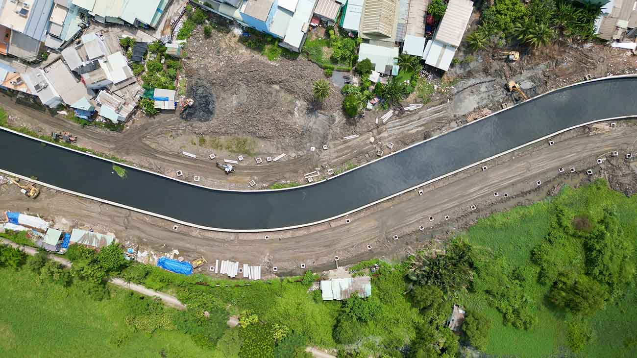 Một đoạn kênh đi qua phường An Lạc đã được gia cố bờ kè, máy xúc đang tiến hành cải tạo hai bên đường.