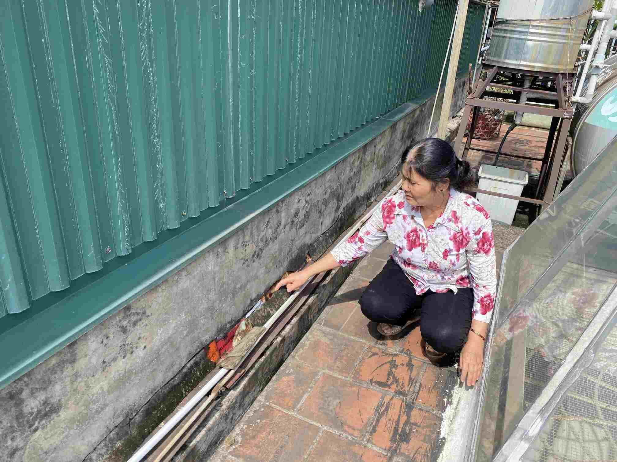 Bà Khanh lo lắng khi khoảng tường tiếp xúc giữa nhà mình và nhà hàng xóm xuất hiện kẽ hở. Ảnh: Anh Vũ
