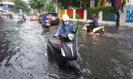 Người dân bì bõm lội nước sau trận mưa lớn trên đường Quốc Hương, tháng 6.2022. Ảnh: Minh Quân