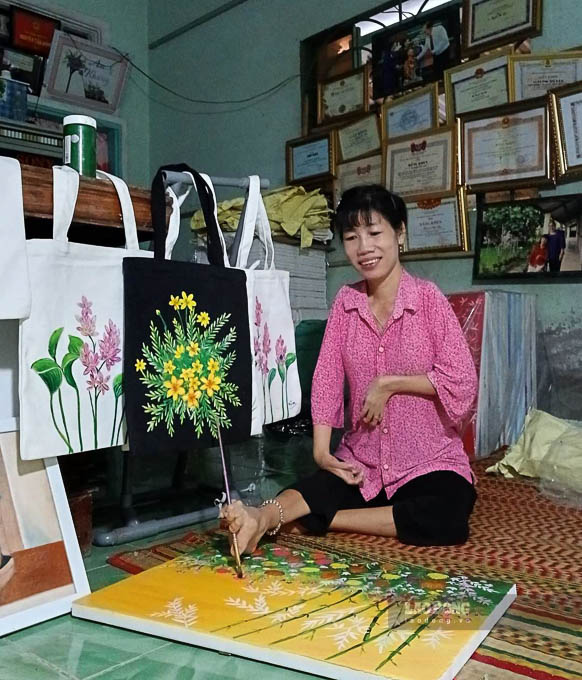 Chị Huỳnh Thị Xậm (Xà Phiên, Long Mỹ, Hậu Giang) đang hoàn thiện một bức tranh bằng đôi chân khiếm khuyết của mình. Ảnh: NVCC